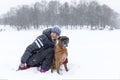 Smiling woman hugging boxer dog in winter park in snowy weather. Love, tenderness and friendship for pets Royalty Free Stock Photo