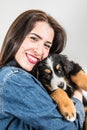 Smiling woman hugs puppy from Bernese mountain dog