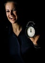 Smiling woman isolated on black showing alarm clock