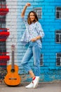 Smiling woman in jeans stands near wall with graffiti next to gu Royalty Free Stock Photo