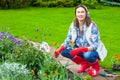 Smiling woman in kerchief and red boots planting flowers