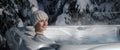 Smiling woman with knitted hat relaxing in outdoor hot tub at snowy winter. banner with copy space Royalty Free Stock Photo