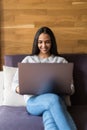 Smiling young woman laying on couch and using laptop Royalty Free Stock Photo