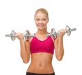 Smiling woman lifting steel dumbbells