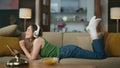 Smiling woman listening earphones laying couch. Happy relaxed girl moving head Royalty Free Stock Photo