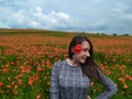 Smiling woman in a long gray dress standing on the red poppy field Royalty Free Stock Photo