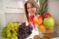 Smiling woman look fruit in refrigerator