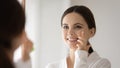 Smiling woman look in mirror apply face cream Royalty Free Stock Photo