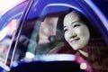 Smiling woman looking through car window at the city nightlife, reflected lights