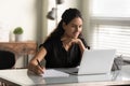 Smiling woman looking at laptop screen, taking notes, studying online Royalty Free Stock Photo