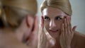 Smiling woman looking in mirror, perfect beautiful skin, rejuvenating injections