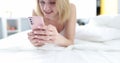 Smiling woman looking into smarphone while lying on phone