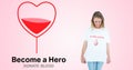 Smiling woman looking at tshirt by become a hero text with blood in heart shape on pink background