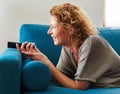 Smiling woman lying down on couch with remote control Royalty Free Stock Photo