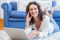 Smiling woman lying on the floor and using her laptop Royalty Free Stock Photo