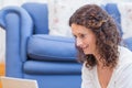 Smiling woman lying on the floor and using her laptop Royalty Free Stock Photo