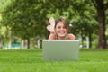 Smiling woman lying on grass and using laptop Royalty Free Stock Photo