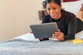 Smiling woman lying on her bed at home looking at her digital tablet Royalty Free Stock Photo