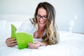 smiling woman lying on her bed reading Royalty Free Stock Photo