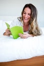 smiling woman lying on her bed reading a book Royalty Free Stock Photo