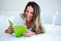 smiling woman lying on her bed reading Royalty Free Stock Photo