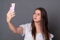 Smiling woman makes selfie on a smartphone. Happy young woman photographs herself on a cell phone