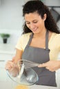 smiling woman making dough with wisk