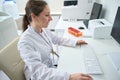 Smiling woman making printout of the results of hematology analyzer Royalty Free Stock Photo