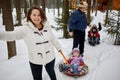 Smiling woman and man ride children on sledge in