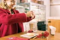 Smiling mature woman with facial wrinkles putting sugar in her coffee