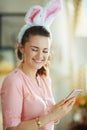 Smiling woman in modern house in sunny spring day writing sms Royalty Free Stock Photo
