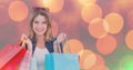 Smiling woman with multi colored shopping bags over bokeh Royalty Free Stock Photo