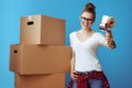 Smiling woman near cardboard box giving tape dispenser on blue Royalty Free Stock Photo