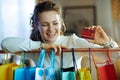 Smiling woman near shopping bags looking at red credit card