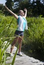 Smiling woman opening her arms wide for mindfulness, sunny outdoors