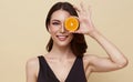 Smiling woman with orange. Photo of beautiful woman with perfect makeup on nude color background. Beauty and Skin care Vitamin C Royalty Free Stock Photo