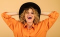 Smiling woman in orange stylish shirt and black hat. Sexy girl with bright makeup and curly hair in black fedora hat Royalty Free Stock Photo