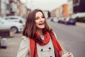 Smiling woman out at evening in the city looking away from camera, portrait in autumn spring wearing beige coat, red scarf Royalty Free Stock Photo