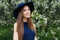 Perfect spring woman in blue hat outdoors. Smiling girl against flowers background Royalty Free Stock Photo