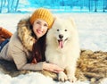 Smiling woman owner and white Samoyed dog lying on snow at winter day Royalty Free Stock Photo