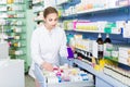 Woman pharmacist is attentively searching medicines in apothecary