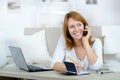 Smiling woman on phone call using laptop