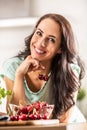 Smiling woman picks two cherries from a seethrough bowl indoors