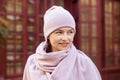 Smiling woman in a pink knitted hat and scarf. Concept lifestyle, autumn, urban