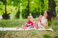 Smiling woman play and sit on green grass in park, rest and hug hold soap bubble blower with little cute child baby girl. Happy Royalty Free Stock Photo