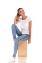 Smiling woman playing with her ponytail sitting on wooden box Royalty Free Stock Photo