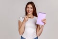 Smiling woman pointing at paper notebook with blank space for commercial text, advertising area. Royalty Free Stock Photo