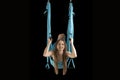 Smiling woman practicing Fly yoga. Intense gymnast training in sports hammock. Aerial gymnastics. Black background