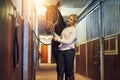 Smiling woman preparing her horse in stables before a ride Royalty Free Stock Photo