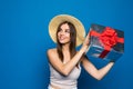 Smiling woman present gift box with red ribbon. Beauty woman isolated on blue studio background. Woman want to know what inside of Royalty Free Stock Photo